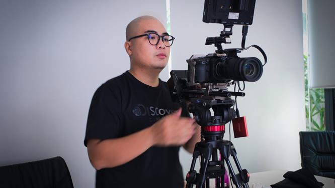 A Saigon Videographer operator filming with a camera on a slider rig indoors.