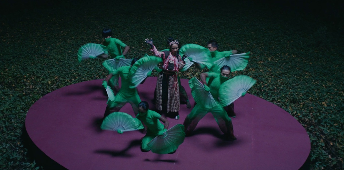 A TRUC Studio stage production with performers in green costume on a lit outdoor set.